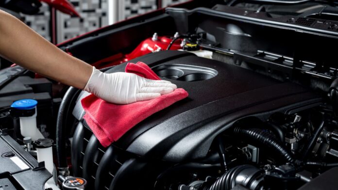A mechanic finishing car servicing with a red cloth